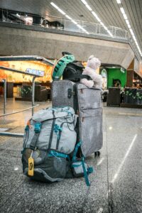 Backpacks and travel bags at an airport during a family backpacking journey, highlighting the difference between travelling and a holiday.